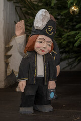 A carved figurine of a miner in front of a Christmas tree.
