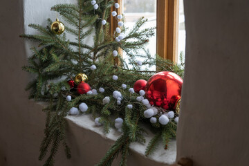 A Christmas decoration with a candle by a wooden window in an interior.
