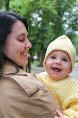 Mother Holding Baby in Yellow Outfit at Park early autumn