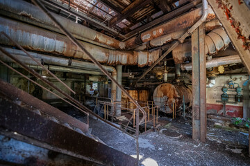 Fototapeta premium Vintage machinery inside an abandoned sugar refinery in Italy. Rusted equipment and industrial decay in a defunct factory hall