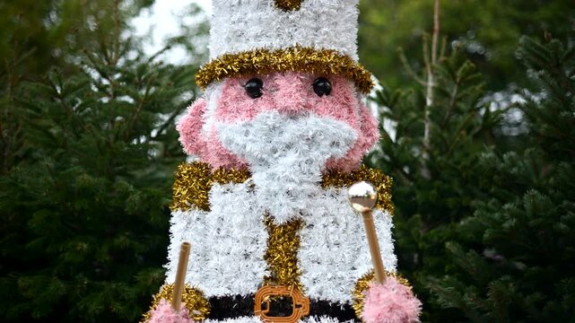 Decorative Christmas nutcracker soldier figure displayed outdoors with trees in the background
