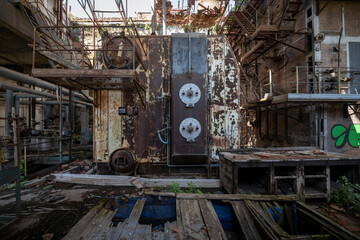 Fototapeta premium Vintage machinery inside an abandoned sugar refinery in Italy. Rusted equipment and industrial decay in a defunct factory hall
