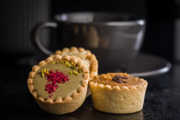 Sweet mini tartlets on black table.