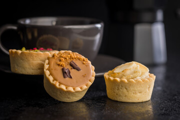 Sweet mini tartlets on black table.