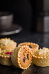 Sweet mini tartlets on black table.