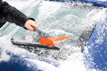 Fototapeta premium Person quickly removing ice from vehicle, Frosty morning routine to clear icy windshield safely