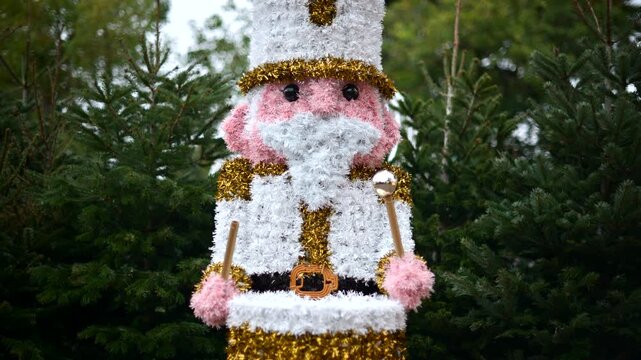 Decorative Christmas nutcracker soldier figure displayed outdoors with trees in the background