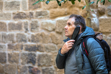 Man contemplating under a tree in a rustic stone courtyard on a calm afternoon