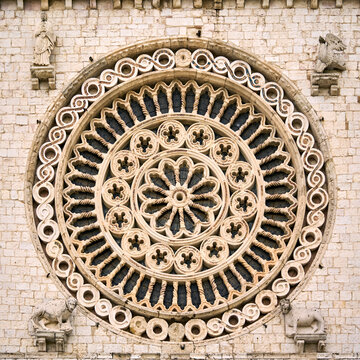 Magnificent medieval rose window featuring intricate architectural tracery on an ancient cathedral facade.