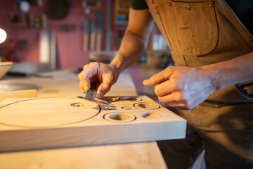 Man carpenter measuring future lamp parts with caliper, ready templates for custom furniture and decor production in workshop. Precision woodworking, handmade design, manufacturing furniture, diy
