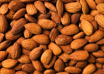 Fototapeta premium Full frame background of roasted almond nuts, close-up texture of brown kernels