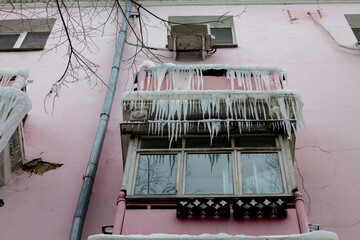 Icicles hanging from the window of a pink building in winter