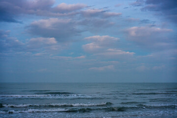 Ocean waves washing dark sand beach at dusk