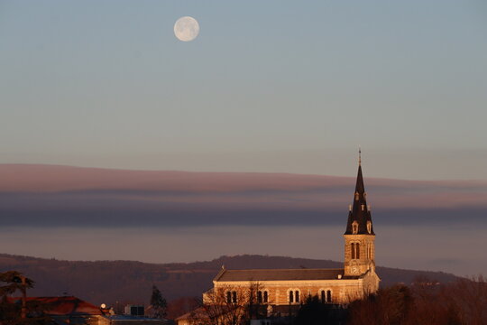 Lune au dessus d'une &eacute;glise &eacute;clair&eacute;e par le soleil levant