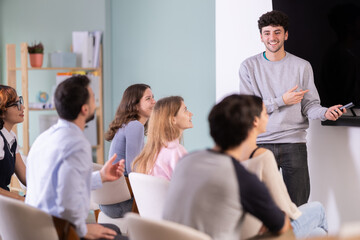 Fototapeta premium Young man gives a presentation to a full class of students. Class for learning foreign languages and additional education. Students listening to the teacher