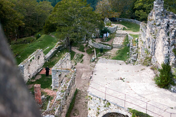Orthodox priest stands contemplatively among ruins of destroyed temple where faith persists amid decay.