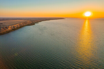 Obraz premium Sunset over calm sea with golden reflection on water surface
