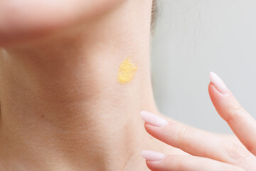 Closeup of a woman applying retinal serum to her neck.