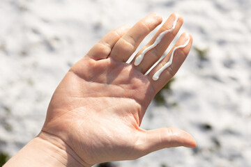 Closeup of a person using the correct amount of sunscreen fir face and neck in winter. 