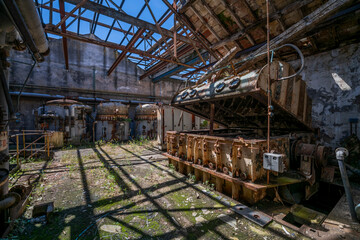 Fototapeta premium Derelict industrial hall of an abandoned Italian sugar mill. Large warehouse ruins with decaying walls and urban exploration atmosphere