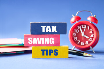 TAX SAVING TIPS - words on colorful wooden blocks with an alarm clock in the background
