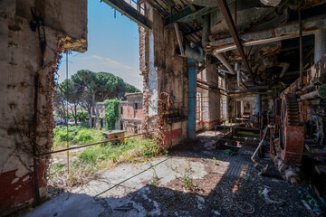 Fototapeta premium Derelict industrial hall of an abandoned Italian sugar mill. Large warehouse ruins with decaying walls and urban exploration atmosphere