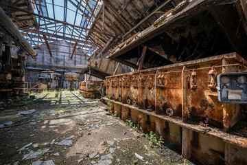 Fototapeta premium Vintage machinery inside an abandoned sugar refinery in Italy. Rusted equipment and industrial decay in a defunct factory hall