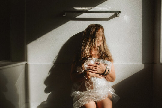 woman sitting in bubble wrap on side of tub