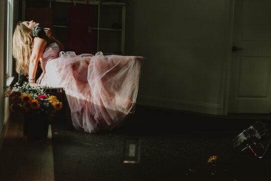 woman looking up holding camera in a pink lace dress