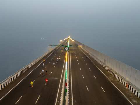 Aerial view of runners participating in a marathon on the Atal Setu bridge, a modern marvel cutting through the misty landscape, Mumbai, Maharashtra, India.