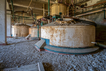 Derelict industrial hall of an abandoned Italian sugar mill. Large warehouse ruins with decaying...