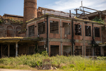 Fototapeta premium Derelict industrial hall of an abandoned Italian sugar mill. Large warehouse ruins with decaying walls and urban exploration atmosphere