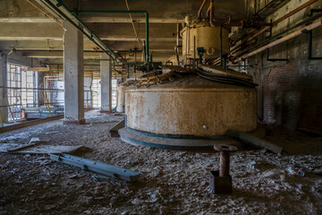 Derelict industrial hall of an abandoned Italian sugar mill. Large warehouse ruins with decaying...