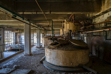 Derelict industrial hall of an abandoned Italian sugar mill. Large warehouse ruins with decaying...