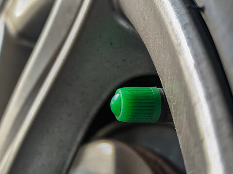 Close up of a green car tire valve cap. Tire valve to control the flow of nitrogen in the tire.