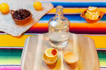 Mezcal bottle with chapulines, lemon, and chili salt