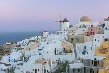 Historic white windmill overlooking the Aegean Sea in Oia village on Santorini island, Greece at sunset.