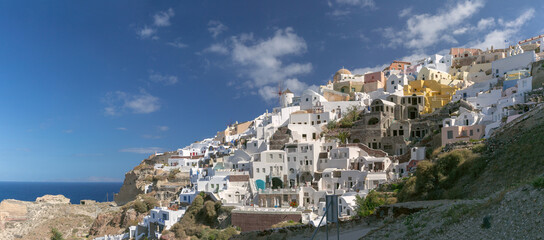 View of traditional windmill and domed church by the sea in Oia village on Santorini island, Greece.