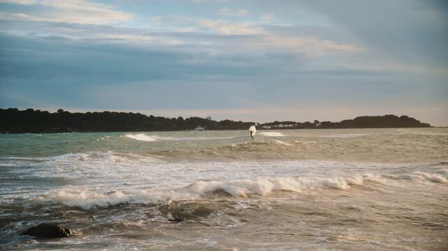 Windsurfer riding waves on the Mediterranean Sea with ile Sainte Marguerite in the background
