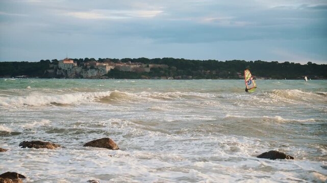 Windsurfer riding waves on the Mediterranean Sea with ile Sainte Marguerite in the background
