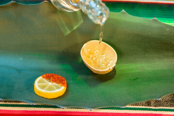 Pouring traditional mezcal into jicara with chili lemon