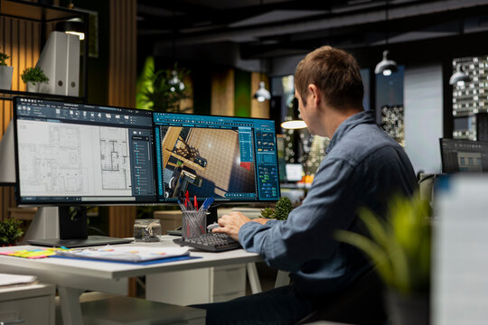 Male employee creates 3D render of an apartment interior using blueprints and architectural software. Using computer aided tools and models to allow customization of flooring and layout.