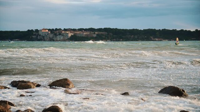 Windsurfer riding waves on the Mediterranean Sea with ile Sainte Marguerite in the background