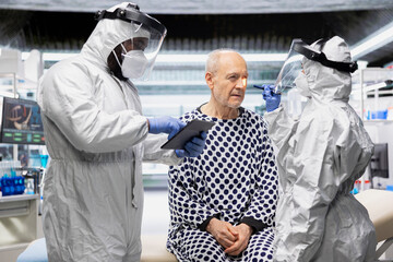 Healthcare professionals in hazmat suits perform diagnostics on patient infected with dangerous virus, studying immunity and vaccination response in a secure biocontainment environment.