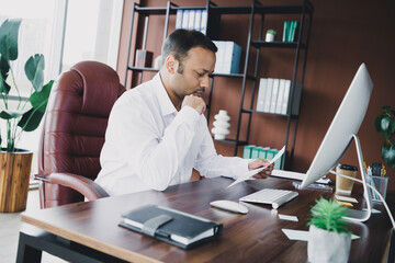 Young handsome business man works at a stylish office desk reviewing documents in a modern loft interior