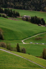 Scenic rolling green hills with a winding path leading to a distant farmhouse and forest
