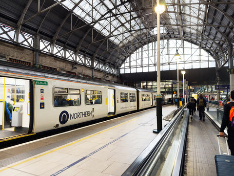 Northern train at Manchester station with glass roof and busy platform