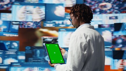 Scientist reviewing medical scans using green screen tablet, 360 degrees rotation. Woman in front of digital health dashboards backdrop analyzing human anatomy with mockup device, camera A close up