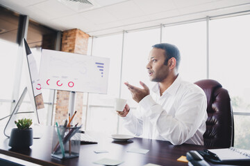 Young handsome businessman presents in a modern loft office at a desk with charts and coffee during a corporate meeting