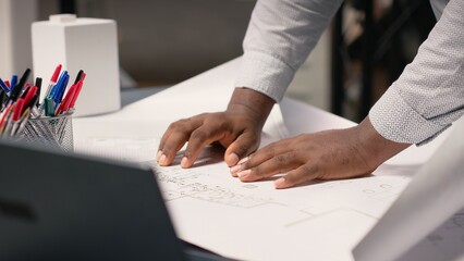 African american contractor examining architectural blueprints plans on table, review zoning regulations for construction project approval. Site preparation master plan and infrastructure.